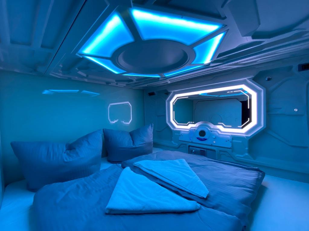 Space Night Capsule Hostel في برلين: غرفة زرقاء مع سرير وتلفزيون