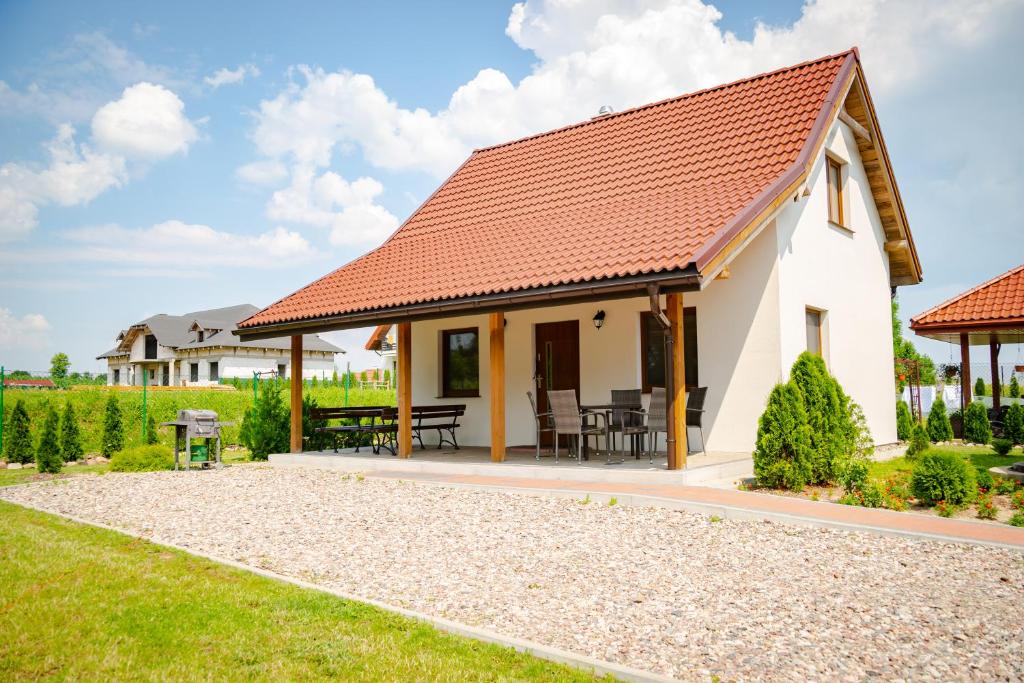 une maison blanche avec un toit rouge dans l'établissement Mazurskie El Dorado, à Mikołajki