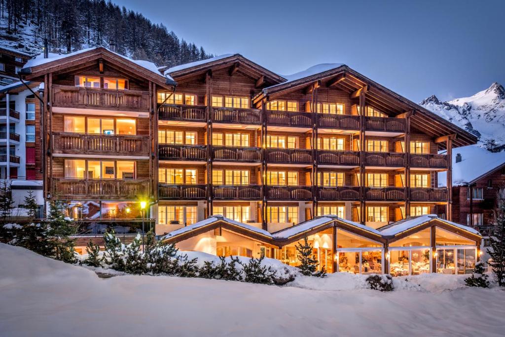 um grande edifício na neve à noite em Wellnesshotel Schweizerhof em Saas-Fee