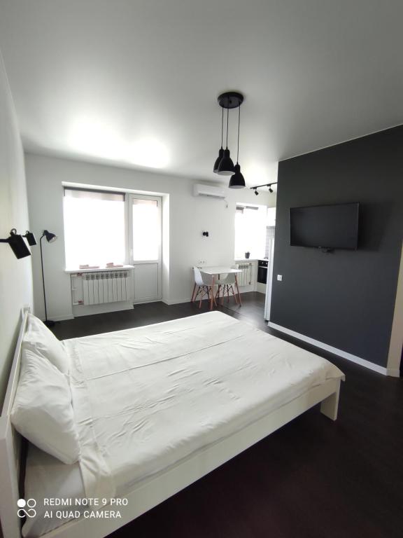 een witte slaapkamer met een bed en een flatscreen-tv bij White Apartment in Poltava