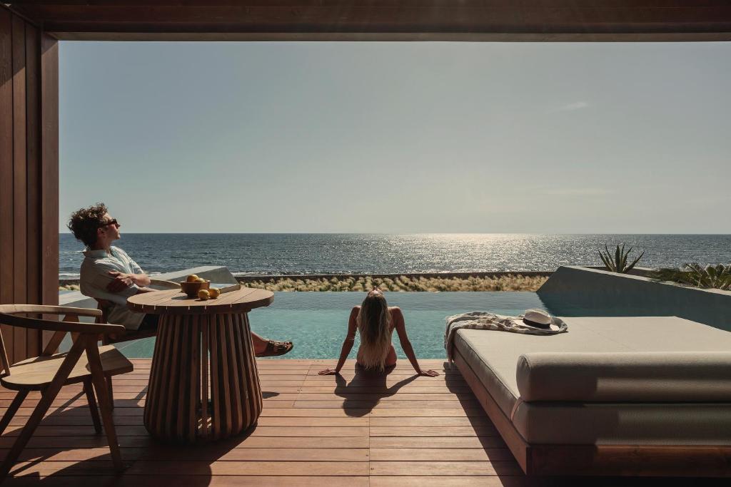 a man and a woman sitting at a table next to a pool at Meraviglia Slow Living in Preveza