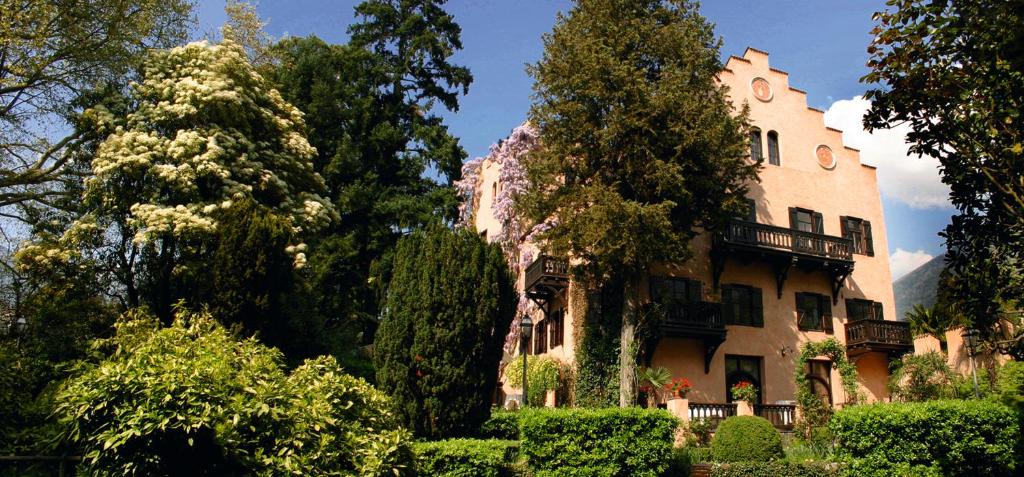 Schloss-Castel Pienzenau - Guestrooms & Apartments - B&B-Hotel & Restaurant في ميرانو: مبنى كبير امامه اشجار