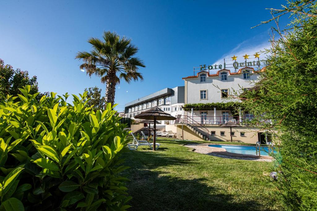 a building with a palm tree and a swimming pool at Hotel Quinta do Viso in Miranda do Corvo