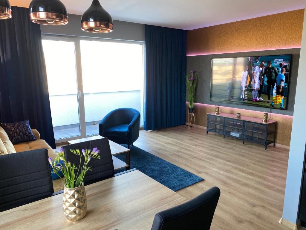 uma sala de estar com uma televisão e um sofá e cadeiras em VIP Apartament-Marine em Rumia