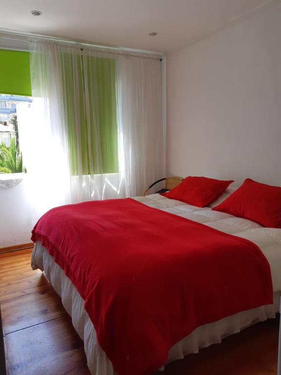 a bedroom with a large red bed with a window at Hostal Magnolio in Viña del Mar