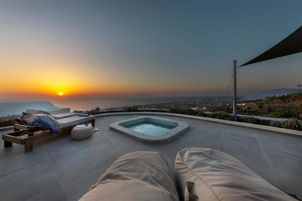 una vasca idromassaggio su un patio con il tramonto sullo sfondo di Villa Vinea Santorini a Imerovigli