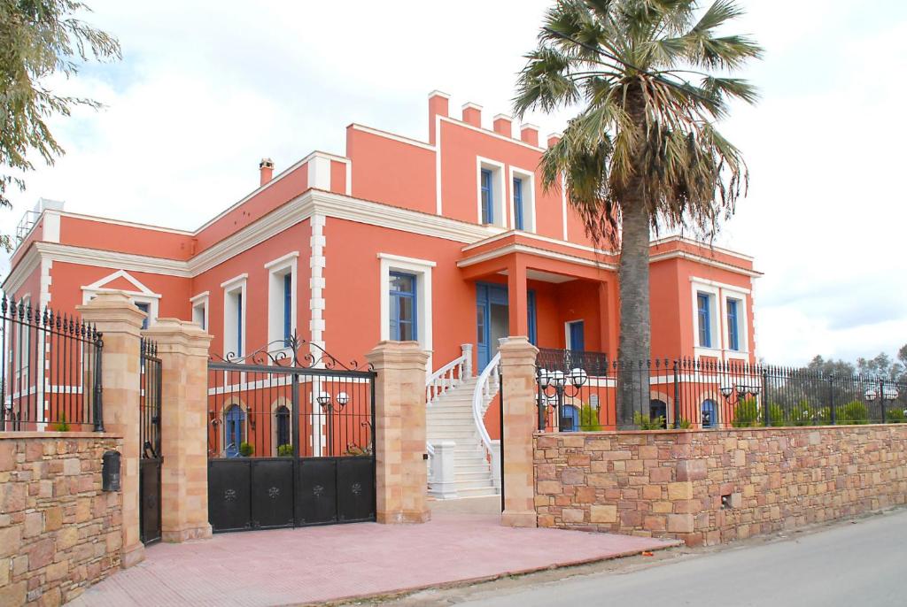 une maison orange avec un palmier en face de celle-ci dans l'établissement Sourediko, à Kambos