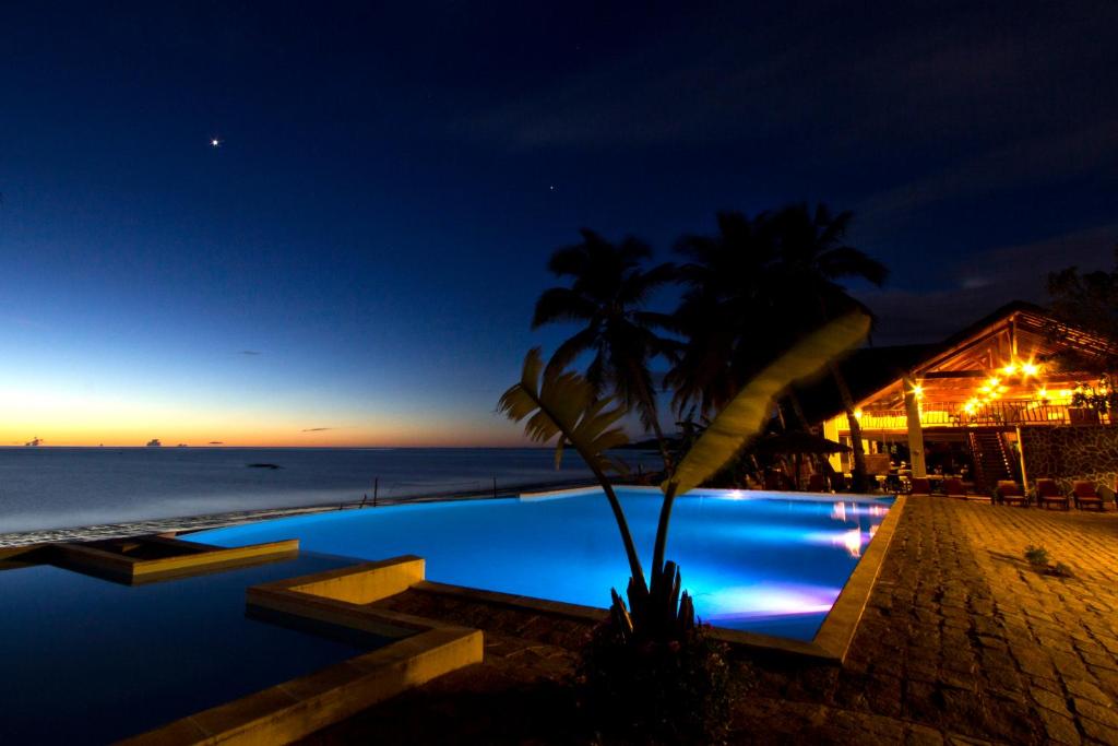 een zwembad in de nacht naast het strand bij Anjiamarango Beach Resort in Nosy Be