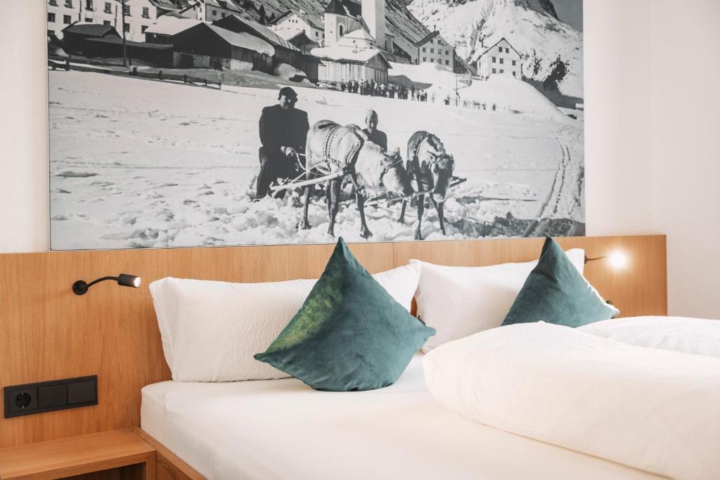 Posto letto in camera d'albergo con una foto appesa al muro. di Apart Garni St Martin - Silvretta Card Premium Betrieb a Galtür