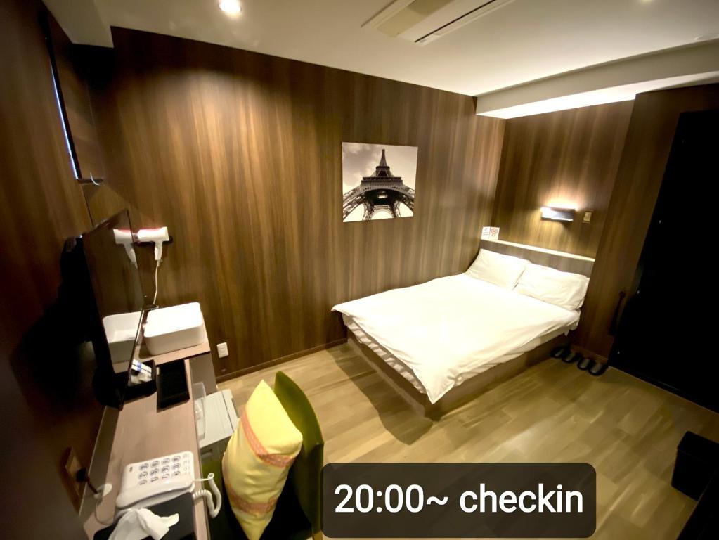 um pequeno quarto com uma cama e uma câmara em Petit Hotel mio em Saitama