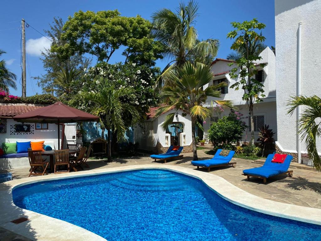 basen z niebieskimi krzesłami i dom w obiekcie Luciano & Grace Apartments w mieście Watamu