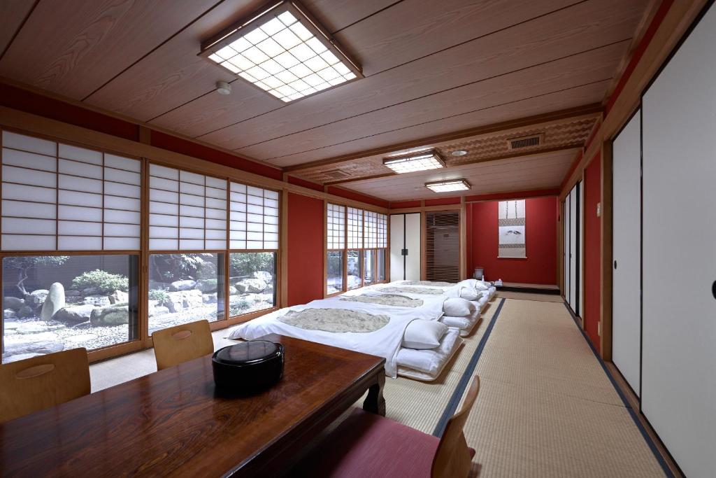 Habitación grande con cama, mesa y ventanas. en Ryokan Yamamuro, en Kanazawa