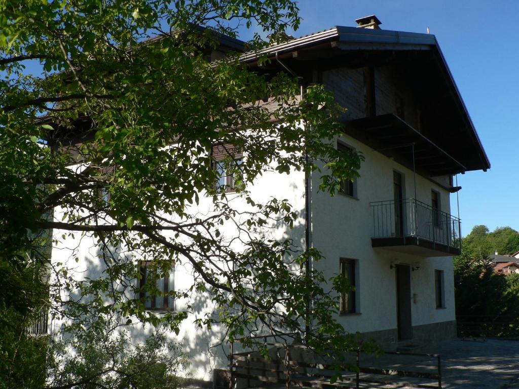 un edificio blanco con balcón y un árbol en La Via del Sole, en Susa