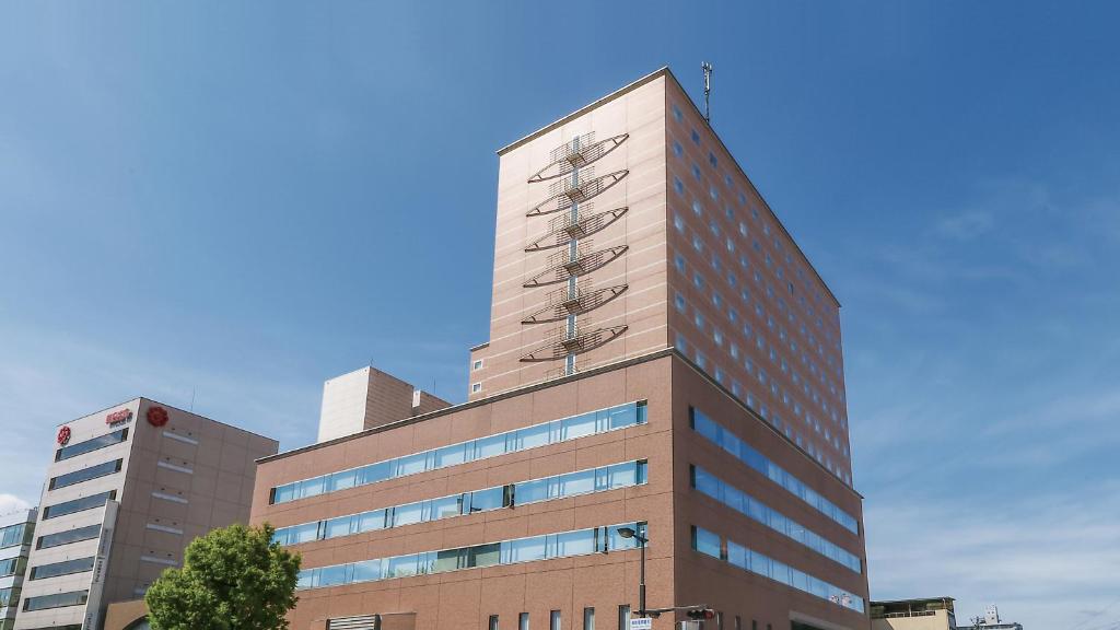 un grand bâtiment avec un ciel bleu en arrière-plan dans l'établissement Hotel Sankyo Fukushima, à Fukushima