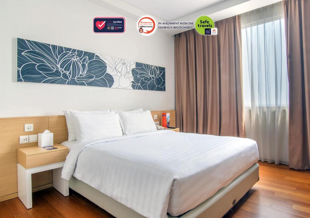 Un dormitorio con una gran cama blanca y una ventana en Swiss-Belinn Airport Jakarta, en Tangerang