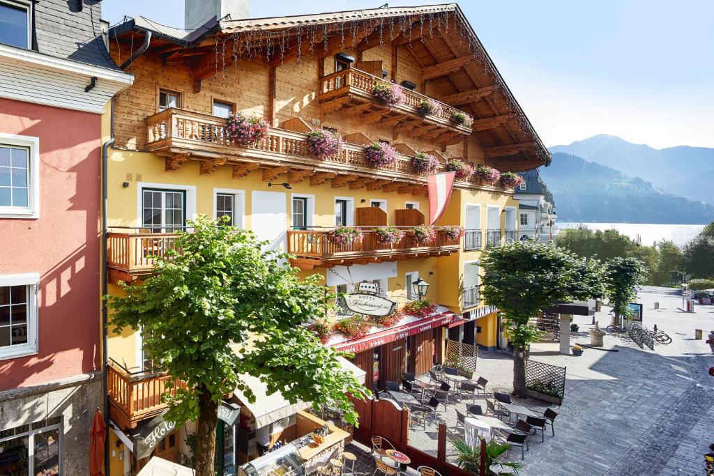 een gebouw met balkons, tafels en stoelen bij Fish'Inn Zell - Hotel Fischerwirt in Zell am See