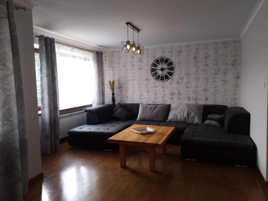 sala de estar con sofá negro y mesa en Apartamenty Kletówka, en Krosno