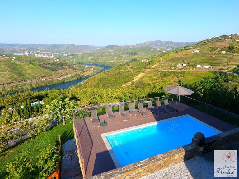 ラメーゴにあるQuinta do Pombal - Douro - Camila'sのプールの景色を望む客室で、椅子とパラソルが備わります。