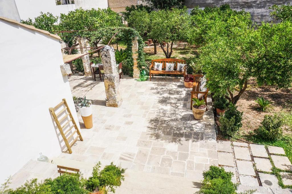 un patio extérieur avec un banc et des arbres dans l'établissement Corte Piri, à Tricase