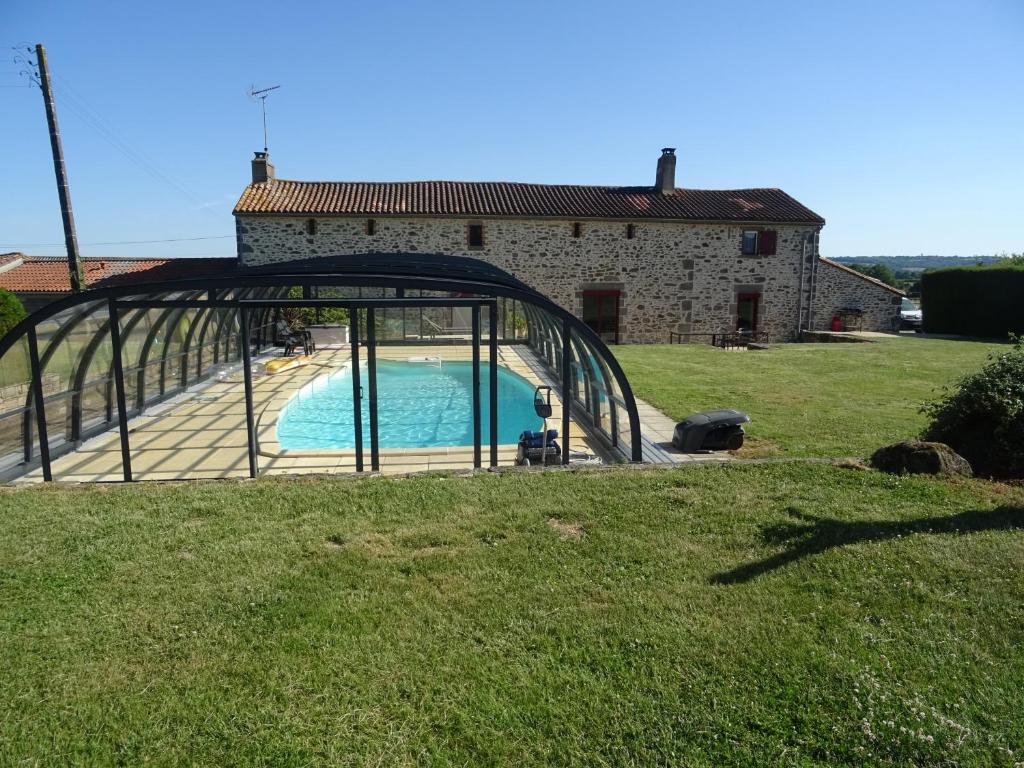 una piscina di fronte a una casa con porta in vetro di La Lauriére a Treize-Vents