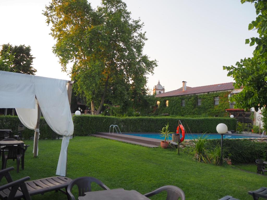 einen Garten mit einem Pool mit Stühlen und einem weißen Zelt in der Unterkunft Casa Dos Gomes in Viseu