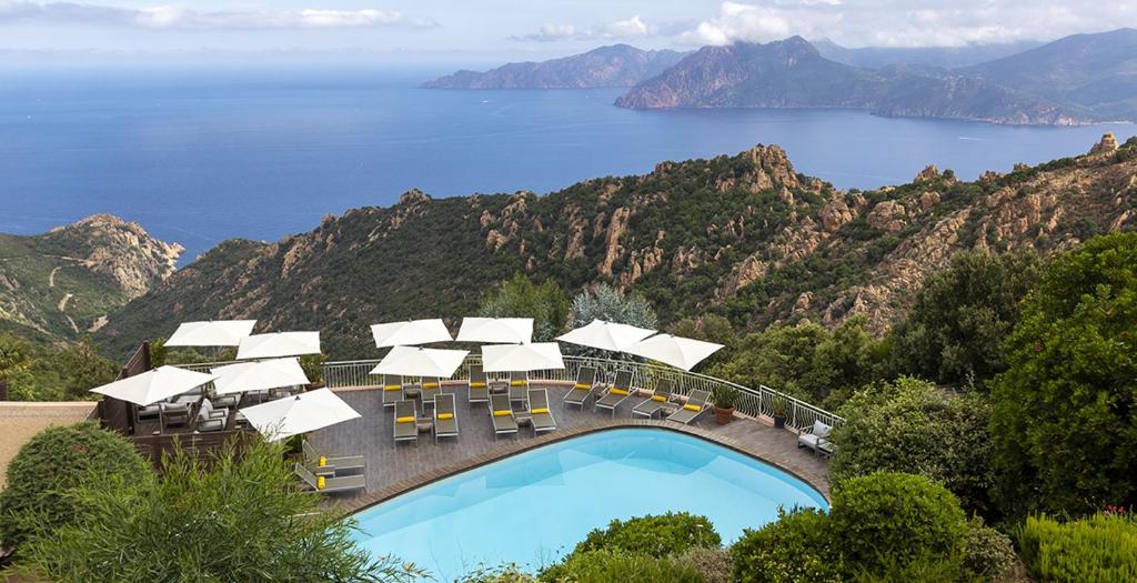 uma piscina com cadeiras e vista para o oceano em Hôtel Capo Rosso em Piana