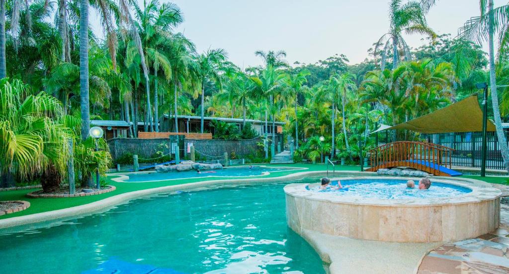 einen Pool in einem Resort mit Leuten darin in der Unterkunft The Palms At Avoca in Avoca Beach