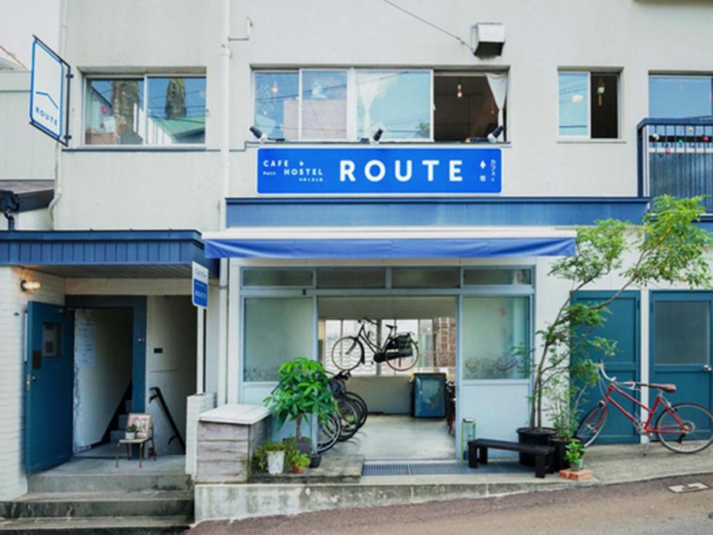 un edificio blanco con una señal de ruta azul en él en ROUTE - Cafe and Petit Hostel, en Nagasaki