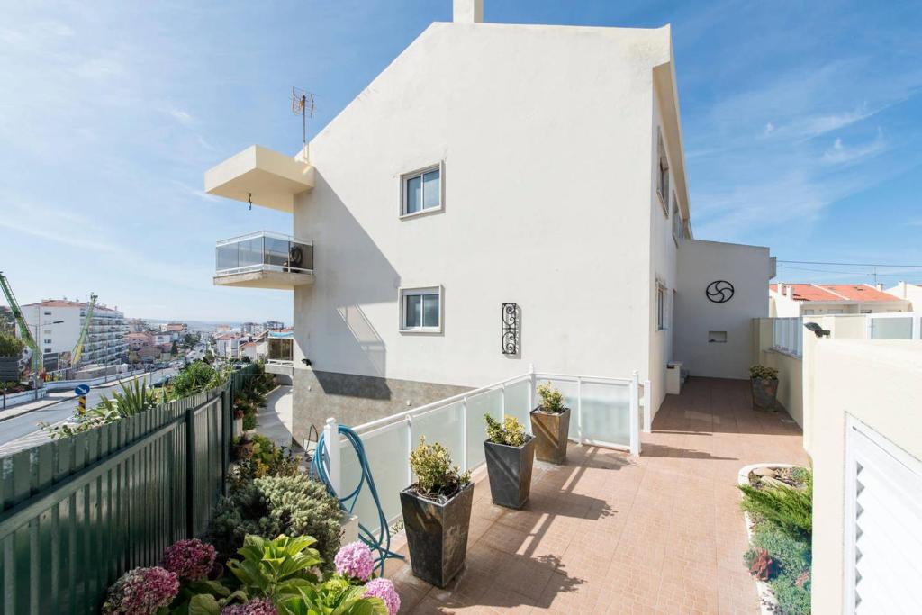 Cette maison blanche dispose d'un balcon avec des plantes. dans l'établissement VIEW CAMÉLIAS HOUSE - 65 SIXTYFIVE BOUTIQUE Home, à Ericeira