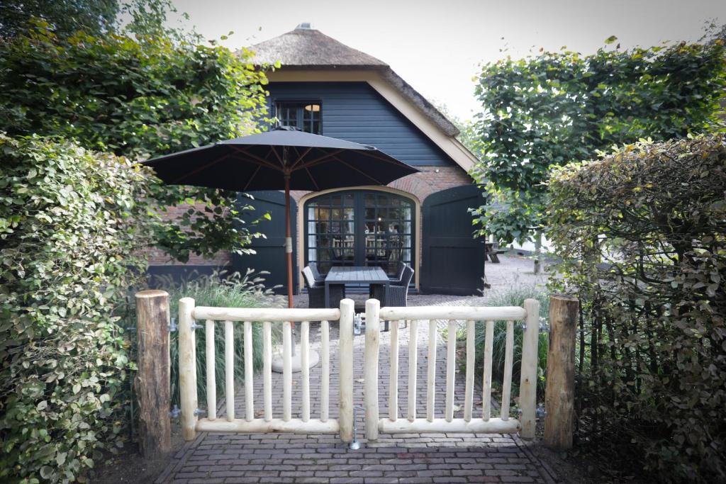 une clôture blanche avec un parasol devant une maison dans l'établissement Lindenhof & Guesthouse, à Garderen