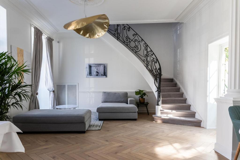 a living room with a staircase with a couch and a chair at Molenmeers Boutique Guesthouses in Bruges