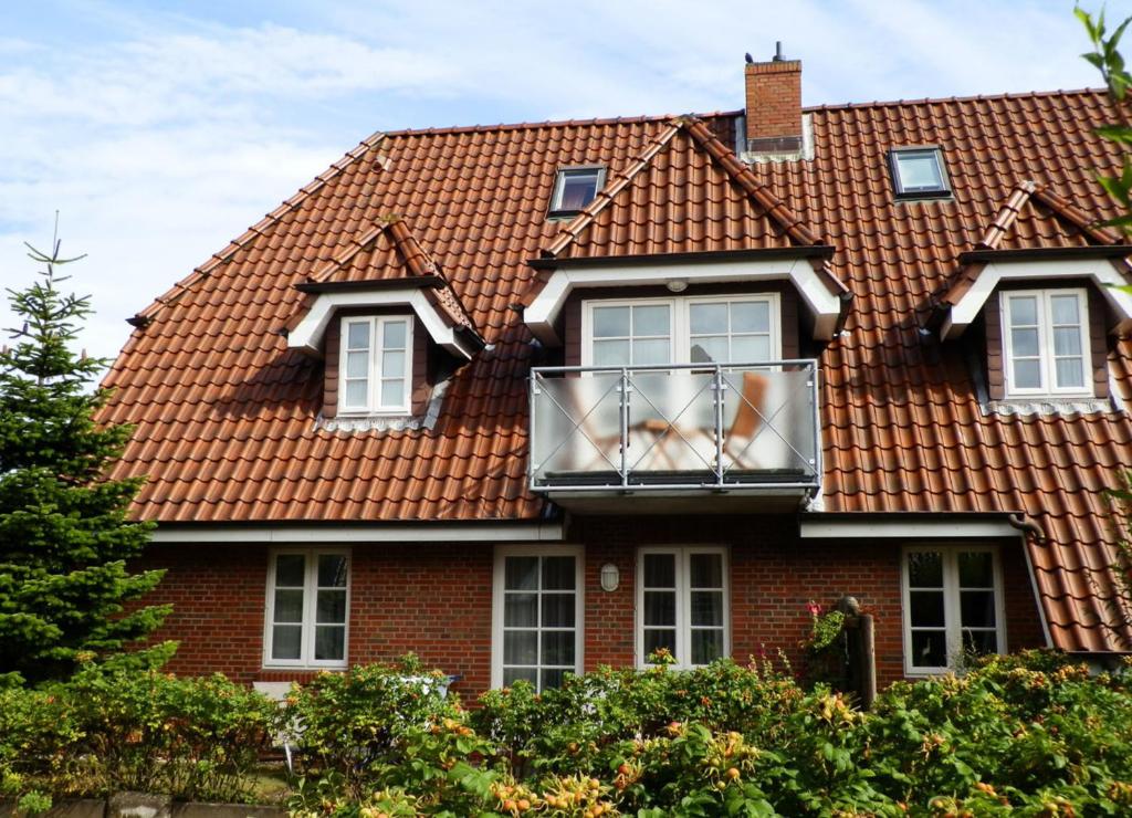 uma casa com um telhado vermelho e uma varanda em Navigare em Wyk auf Föhr