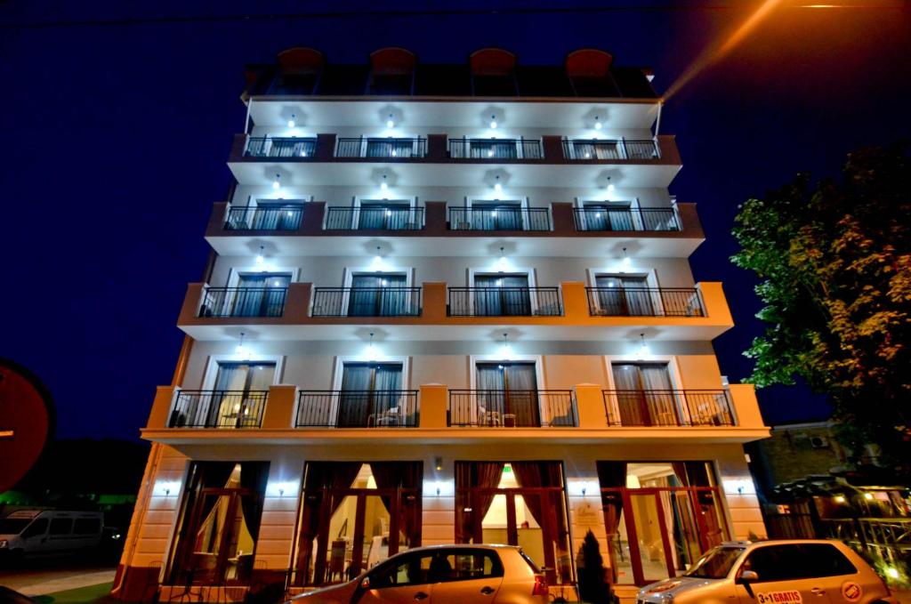 un alto edificio bianco con macchine parcheggiate di fronte di Lucas Boutique Hotel a Eforie Nord