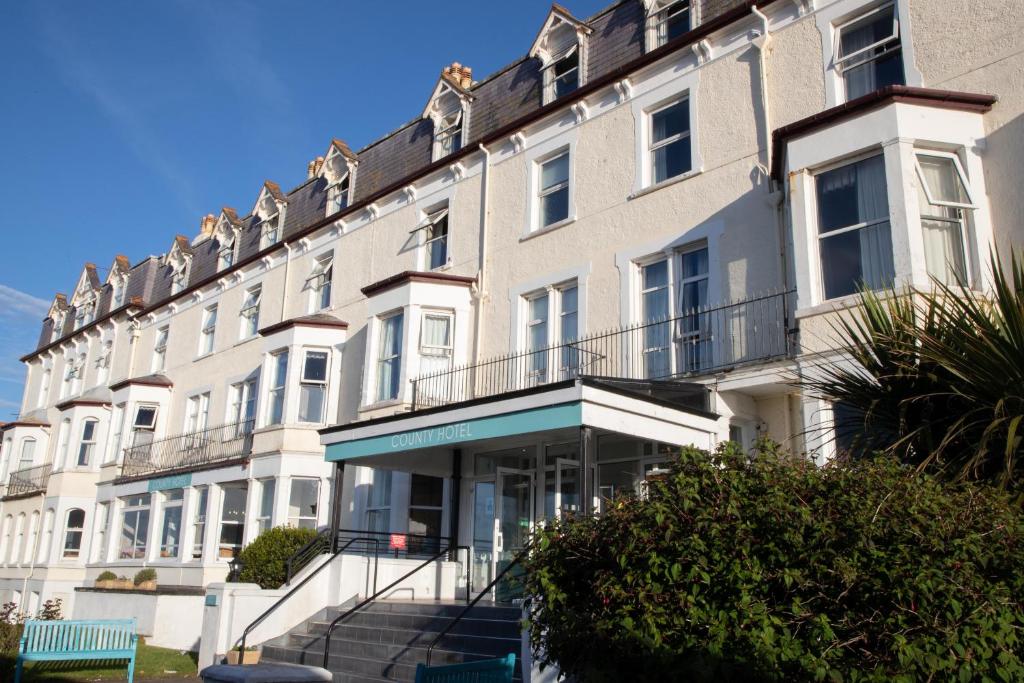 een groot wit gebouw met een trap ervoor bij The County Hotel in Llandudno