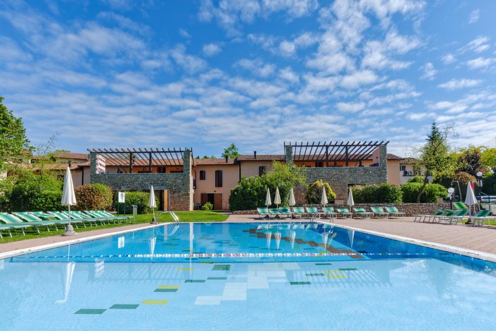 une grande piscine avec des chaises et un bâtiment dans l'établissement Golf Residenza, à Peschiera del Garda