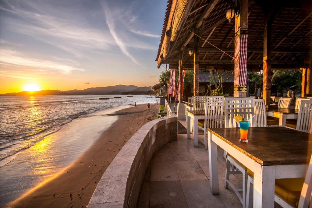 un restaurante en la playa al atardecer en Bali Santi Bungalows, en Candidasa