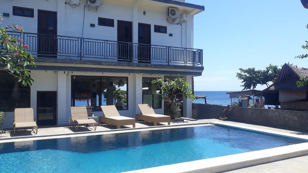 una piscina di fronte a un edificio con sedie di Pakel's Bali Villas ad Amed