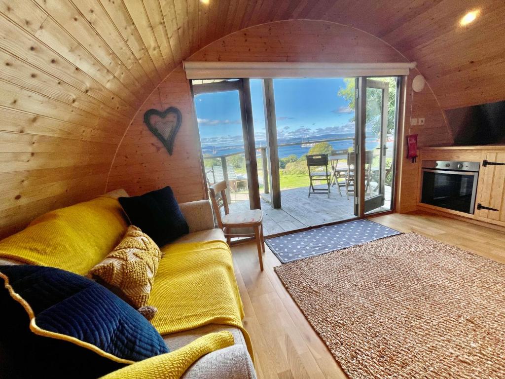 een woonkamer met een bank en uitzicht op de oceaan bij Sutor Coops The Den with Hot Tub in Cromarty