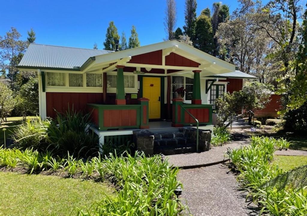 ein kleines rotes und gelbes Haus mit gelber Tür in der Unterkunft Volcano Teapot Cottage in Volcano