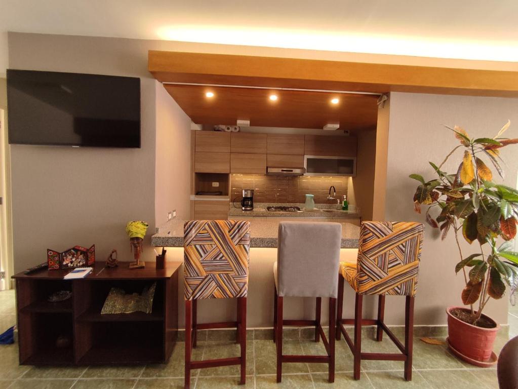 a kitchen with a bar with two chairs and a table at Lilium Apartment & Experiences in Arequipa