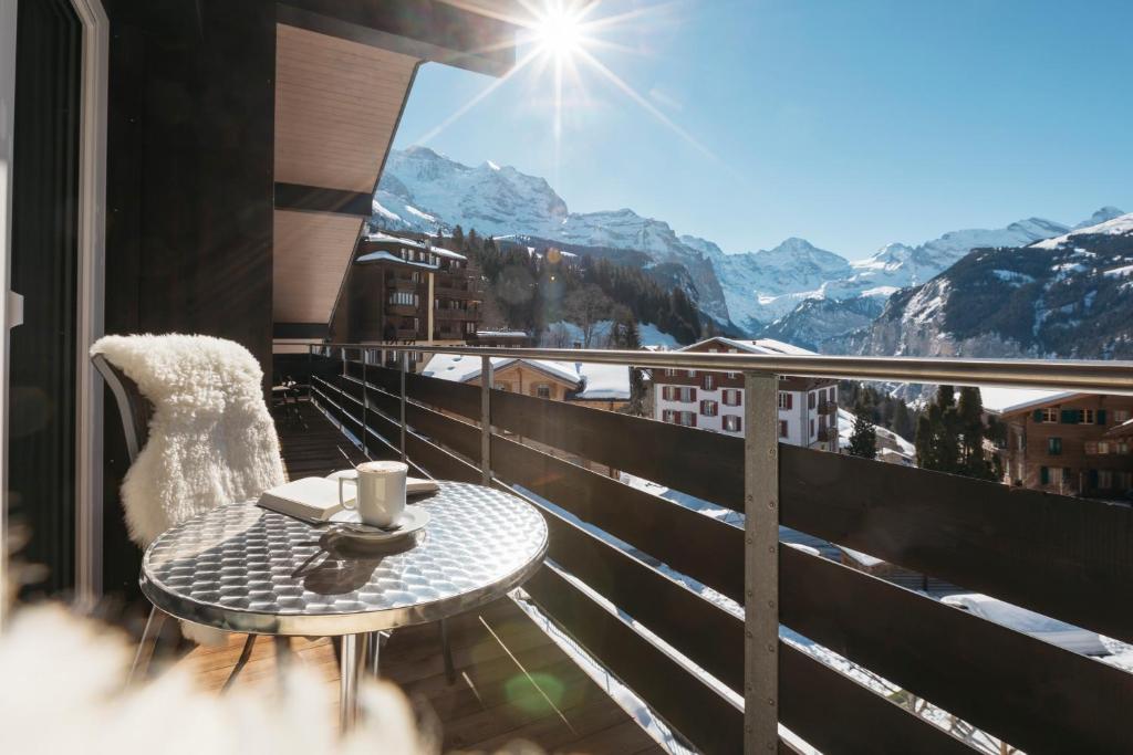 d'une table et d'une chaise sur un balcon avec vue sur les montagnes. dans l'établissement Alpenkräuter Hotel Bären, à Wengen