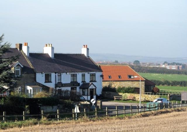 uma casa branca com uma cerca ao lado de um campo em The Windmill Inn - Whitby em Whitby