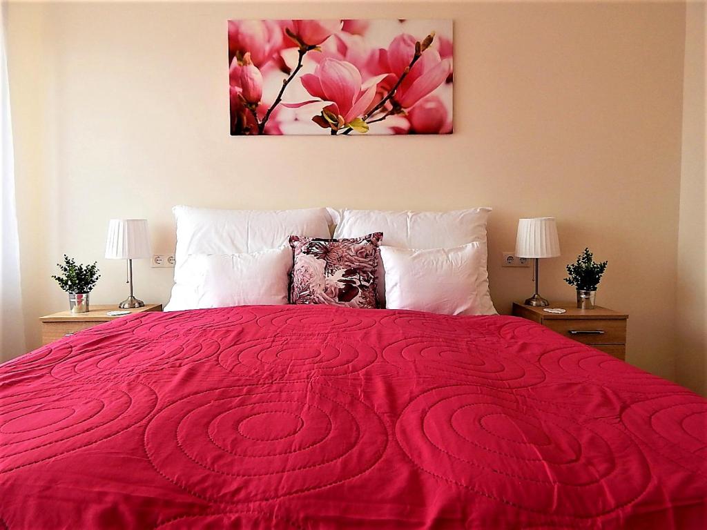 a bedroom with a large red bed with two lamps at Bogácsa Apartman in Bogács