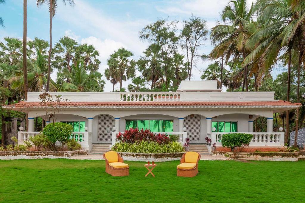 ein weißes Haus mit Stühlen im Hof in der Unterkunft StayVista's Villa Bharat - Beachfront serenity with A spacious lawn in Mumbai