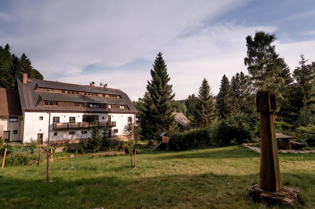 um grande edifício branco num campo ao lado de uma floresta em Pension Styl em Bedřichov