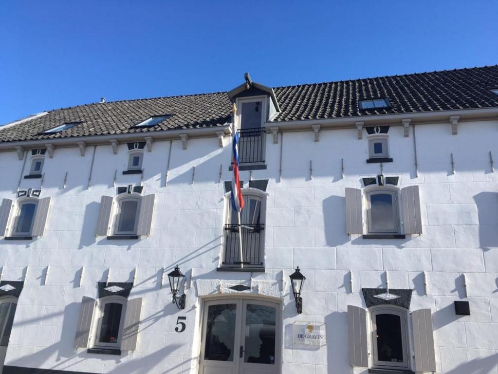 un grand bâtiment blanc avec drapeau. dans l'établissement Hotel De Gravin, à s-Gravenzande