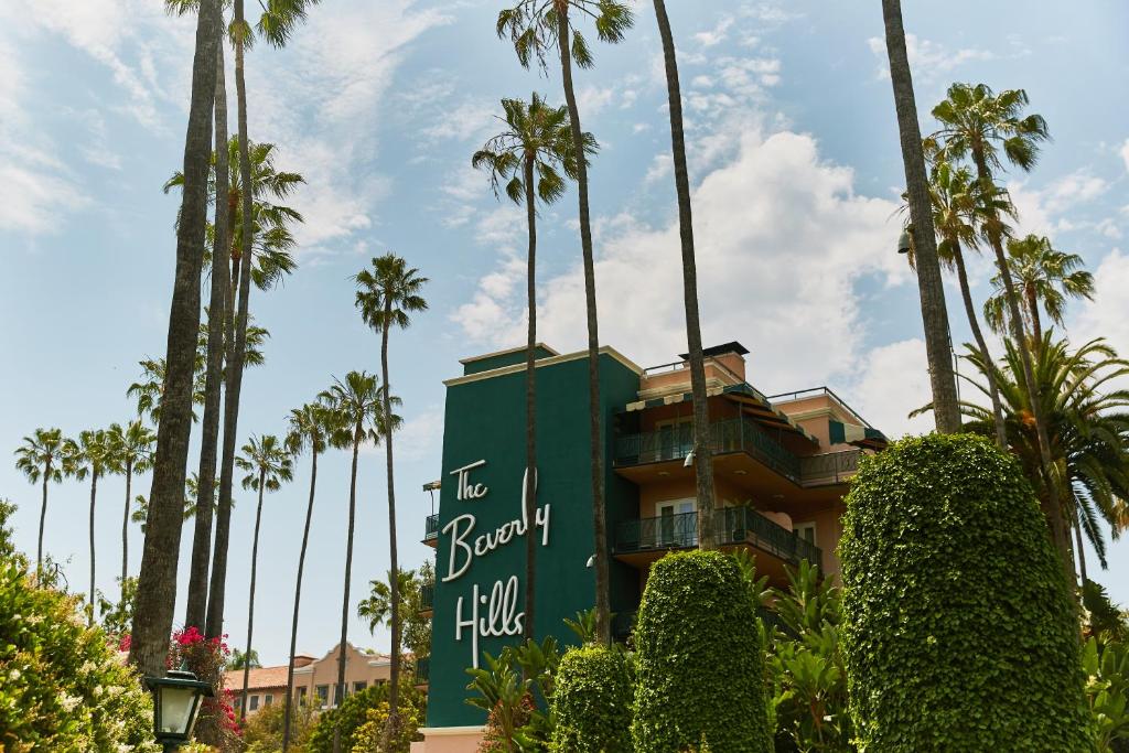 a building with palm trees in the background at The Beverly Hills Hotel - Dorchester Collection in Los Angeles