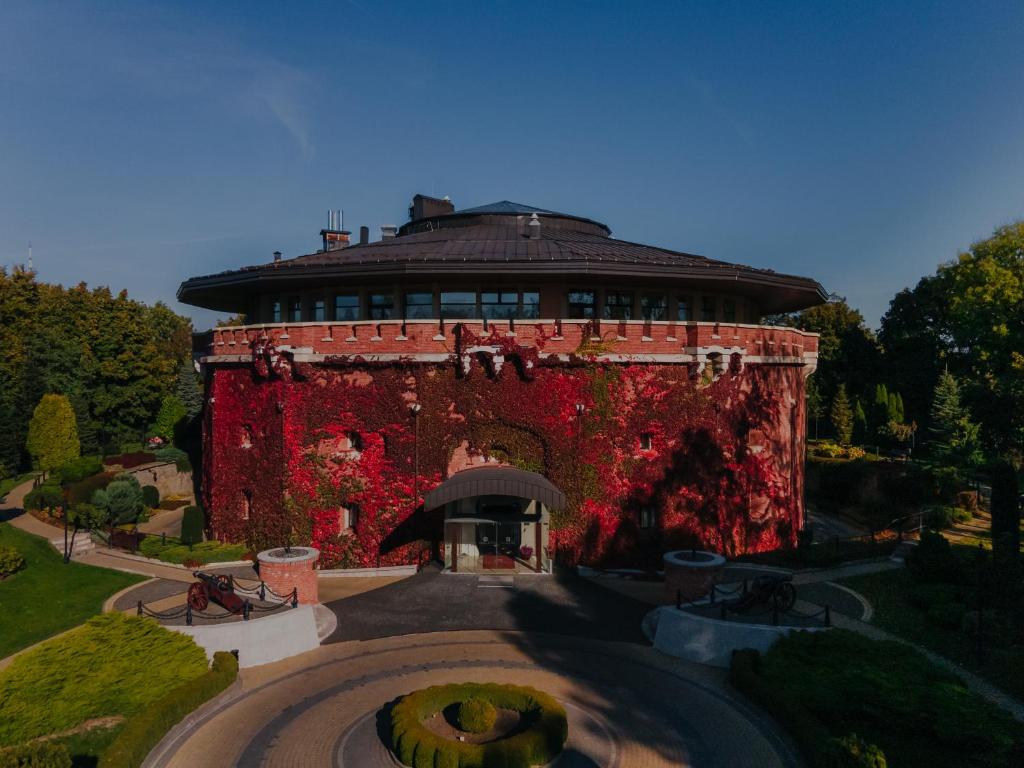 um grande edifício de tijolos com um jardim em frente em Citadel Gastro Boutique Hotel em Lviv