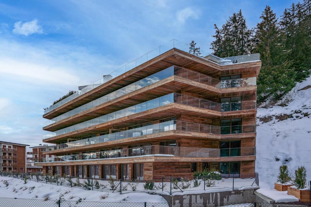 een groot gebouw met sneeuw op de grond bij Sport Club Residences & Spa in Crans-Montana