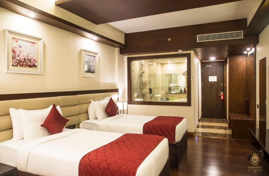 a hotel room with two beds and a window at KPM TRIPENTA HOTEL in Kozhikode